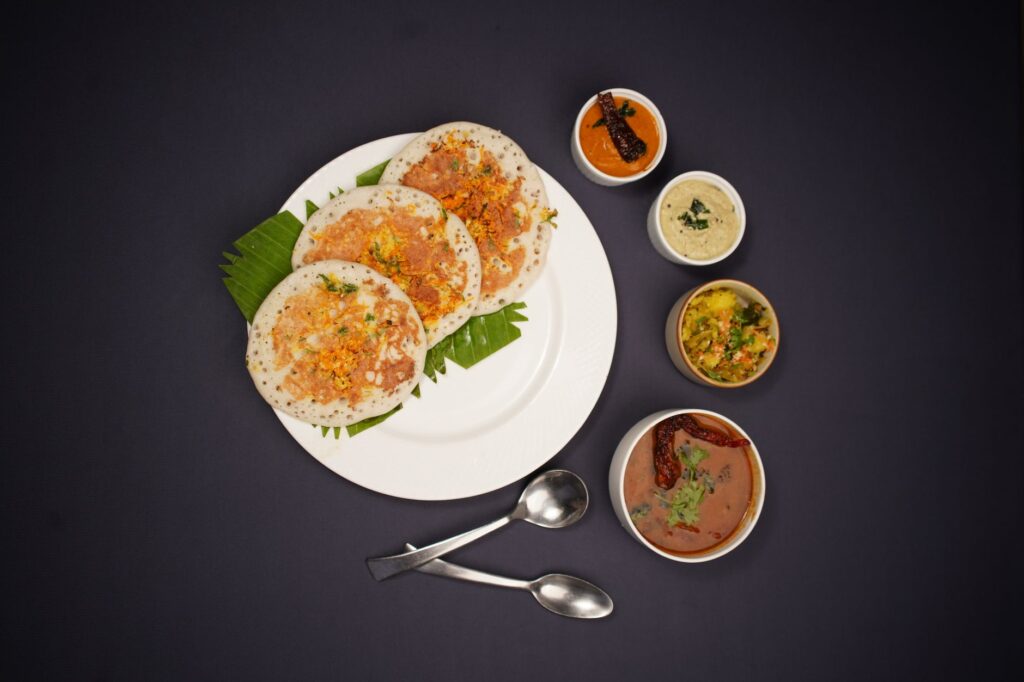 Vue de dessus d'un dosa du Sud de l'Inde servi avec une variété de chutneys sur un fond noir.