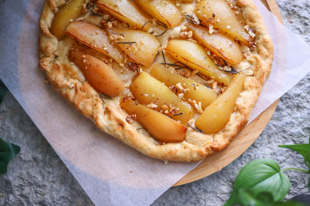Délicieuse tarte aux poires maison avec des ingrédients frais sur une table rustique.
