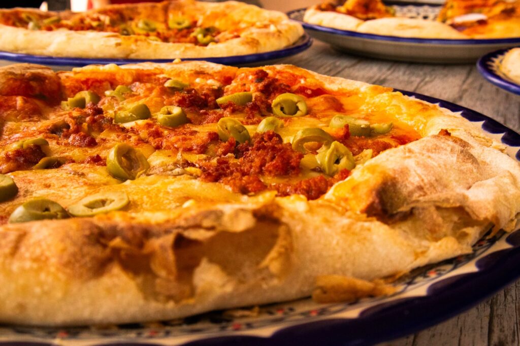 Pizza délicieuse garnie d'olives vertes et de fromage fondu, parfaite pour le dîner ou le déjeuner.