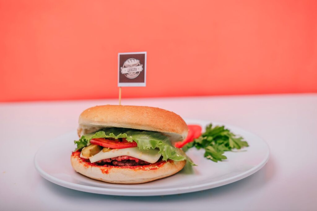 Un burger végétarien avec de la laitue, du fromage et des tomates sur une assiette contre un fond vibrant.