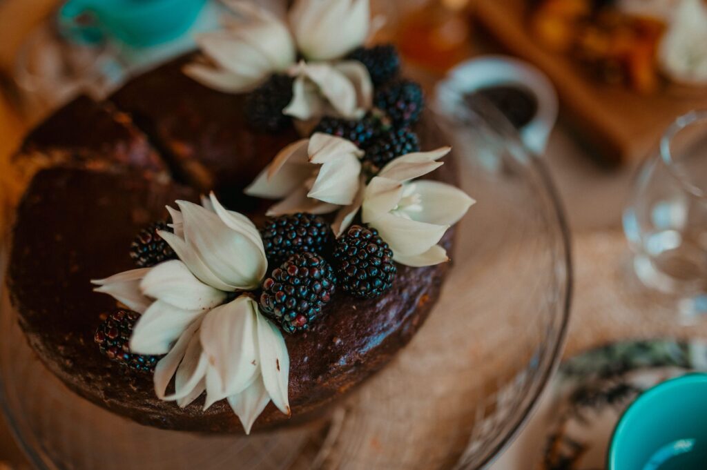 Gros plan sur un gâteau au chocolat décoré de mûres et de fleurs blanches, parfait pour des rassemblements élégants.