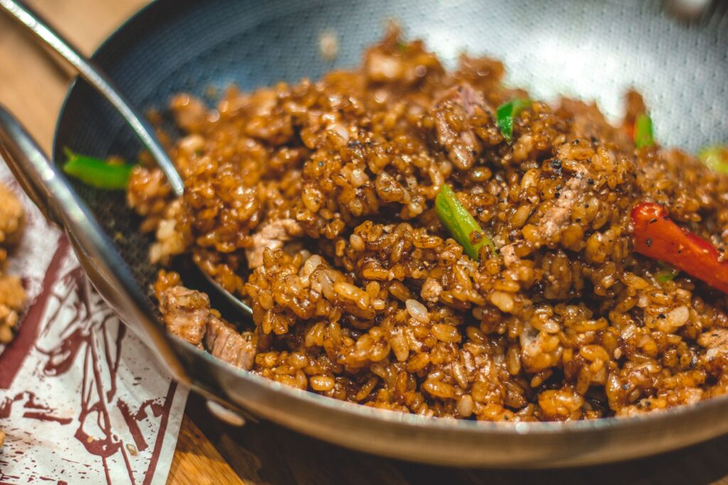 Gros plan sur du riz frit taïwanais avec des légumes et des épices sautés dans un wok. Parfait pour les amateurs de cuisine asiatique.