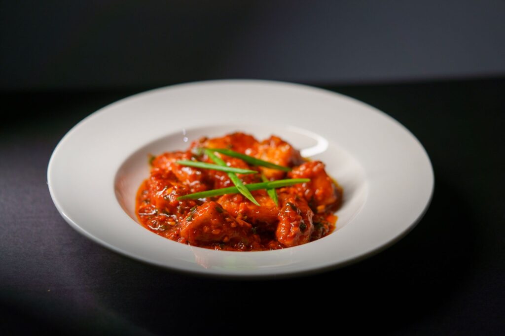 Spicy paneer tikka indien servi dans une sauce riche à base de tomate, garni de cebettes.