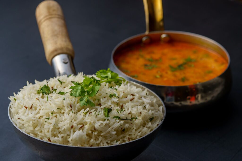 Un plat savoureux de dal indien avec du riz aromatique garni de coriandre fraîche, servi dans des ustensiles traditionnels.