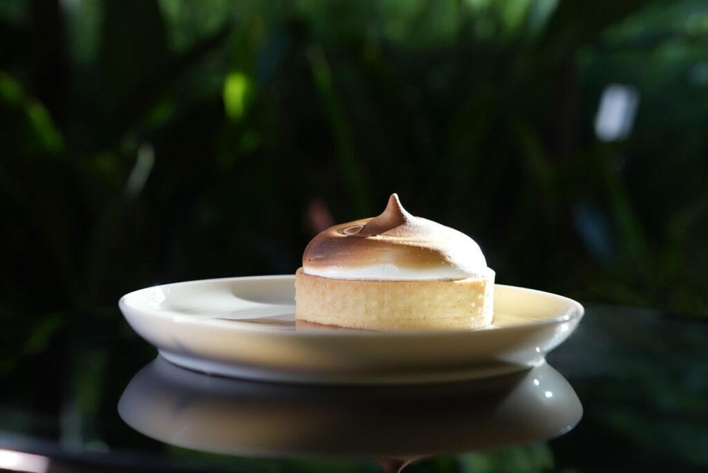 Gros plan sur une tarte au citron meringuée avec des sommets dorés sur une assiette, isolée.