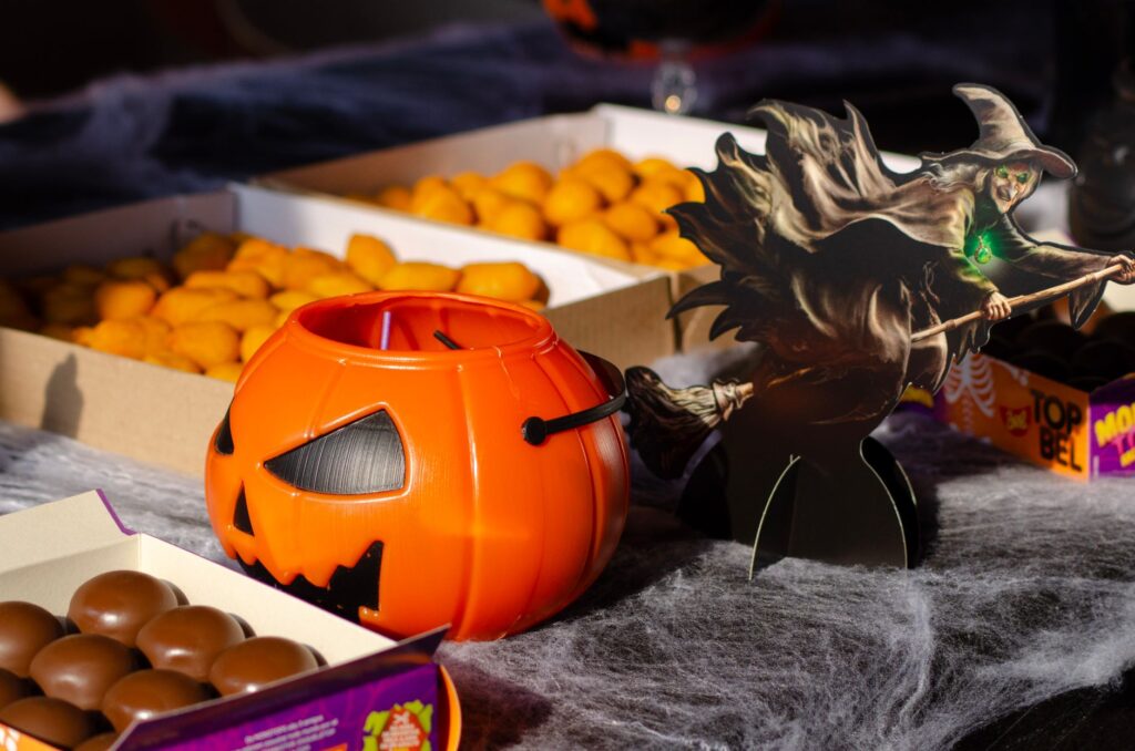 Arrangement festif de bonbons d'Halloween avec un seau en citrouille et une découpe de sorcière.