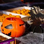 Arrangement festif de bonbons d'Halloween avec un seau en citrouille et une découpe de sorcière.