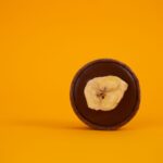 Une photo minimaliste d'une tarte au chocolat garnie d'une tranche de banane sur un fond jaune audacieux.