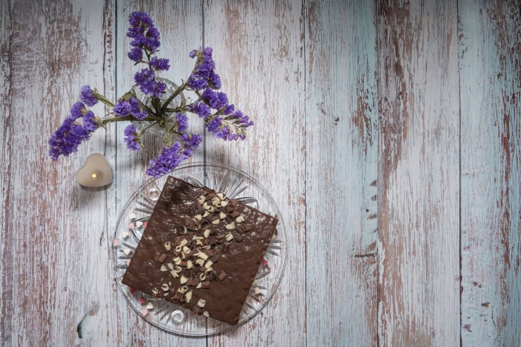 Brownie au chocolat sur une table rustique avec de délicates fleurs violettes et une bougie, cadre de dessert parfait.