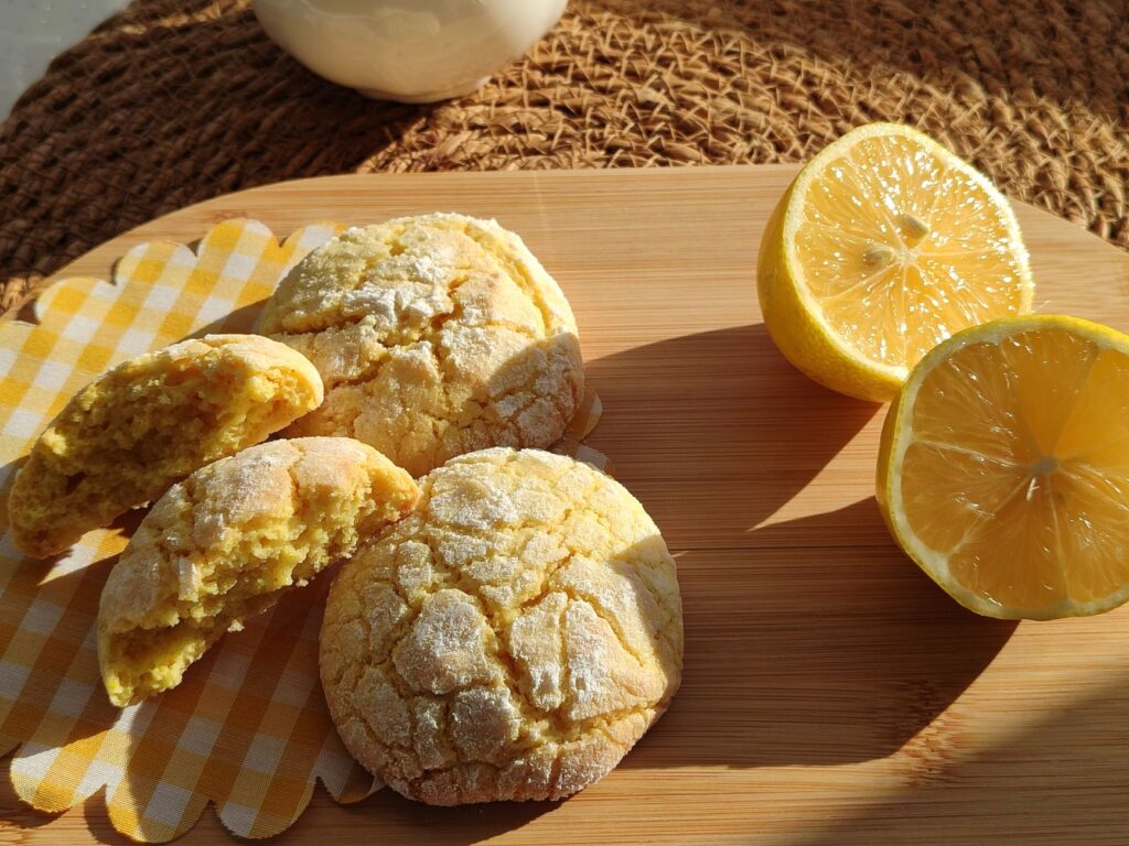 Biscuits au citron fraîchement cuits avec des citrons coupés en deux sur un plateau en bois sous le soleil.