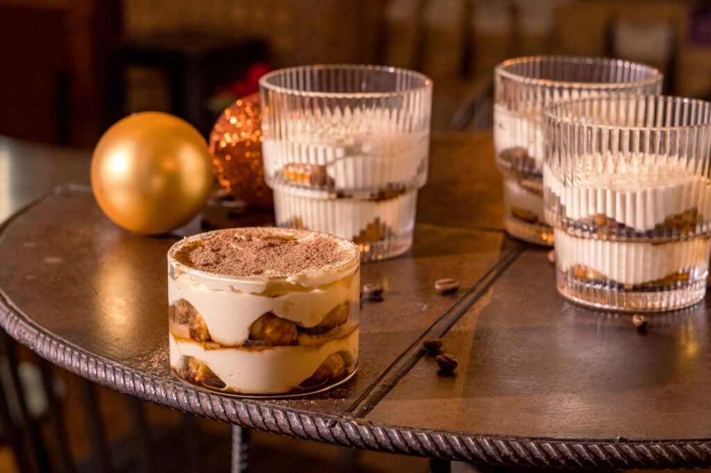 Délicieux dessert tiramisu servi dans un environnement de café chaleureux avec des ornements festifs.