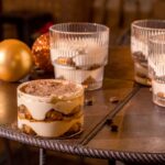Délicieux dessert tiramisu servi dans un environnement de café chaleureux avec des ornements festifs.