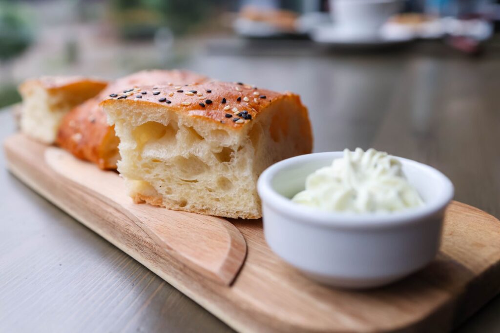 Gros plan d'une tranche de pain focaccia aux graines de sésame, servie avec du fromage à la crème.