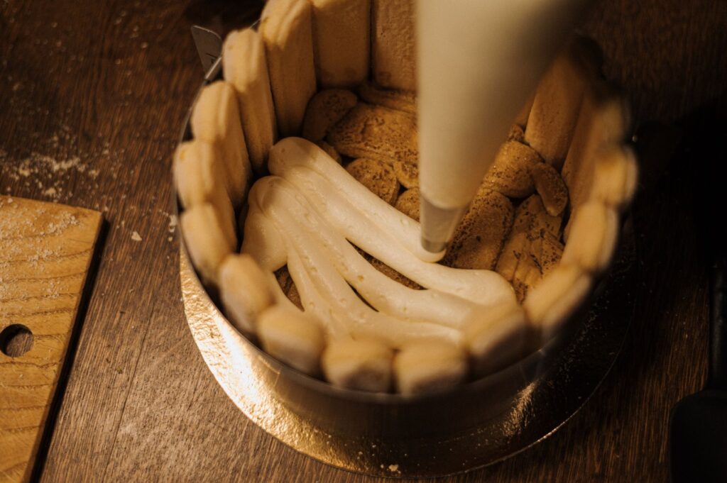 Gros plan de crème dressée sur une base de biscuit pour un gâteau, idéal pour une inspiration de pâtisserie maison.
