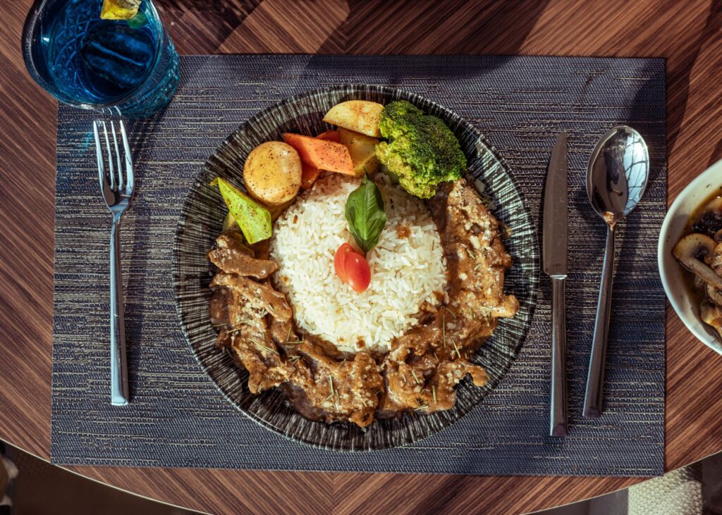 Un délicieux plat de bœuf Stroganoff avec du riz et des légumes servi sur une table.