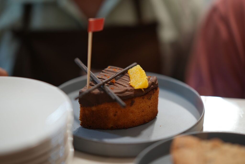 Gros plan d'un gâteau au chocolat et à l'orange avec une décoration de drapeau, servi sur une assiette bleue.
