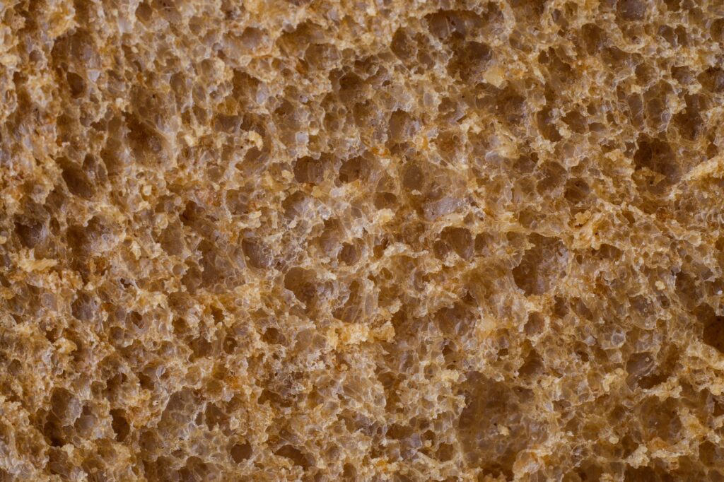 Gros plan détaillé du pain de blé entier montrant sa texture unique et sa structure poreuse.
