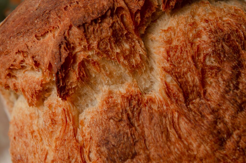 Gros plan détaillé d'une croûte de pain brun doré, mettant en valeur sa texture et sa qualité artisanale.