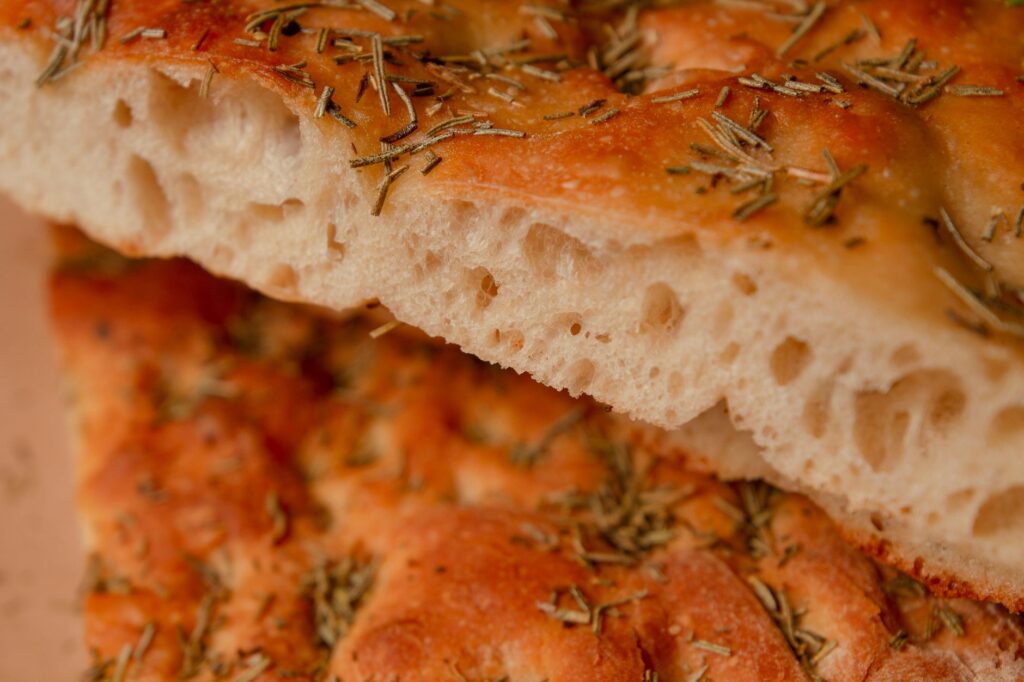 Pain focaccia frais et doré garni d'herbes, parfait pour des projets culinaires.
