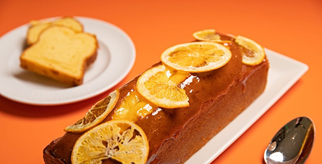 Délicieux gâteau aux agrumes garni de tranches de citron, servi avec des tranches supplémentaires sur une assiette blanche.
