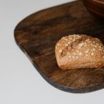 Une petite boule de pain complet fraîchement cuite avec des flocons d'avoine reposant sur une planche en bois rustique.