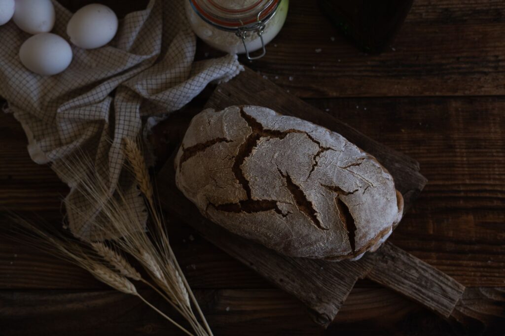 Prise artistique de pain rustique fait maison avec des œufs et du blé sur une table en bois.