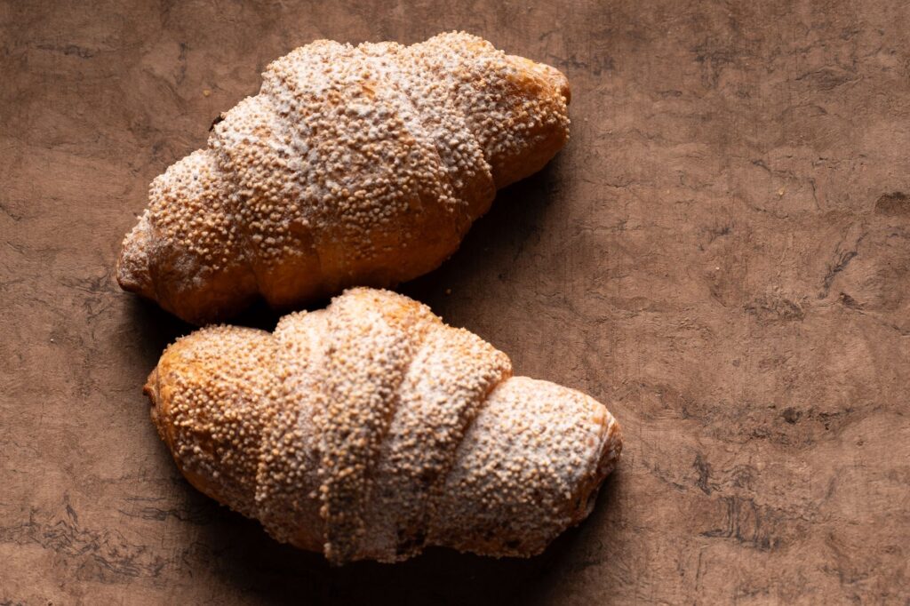 Croissants appétissants avec du sucre en poudre sur une table en bois texturée, parfaits pour l'imagerie du petit-déjeuner.
