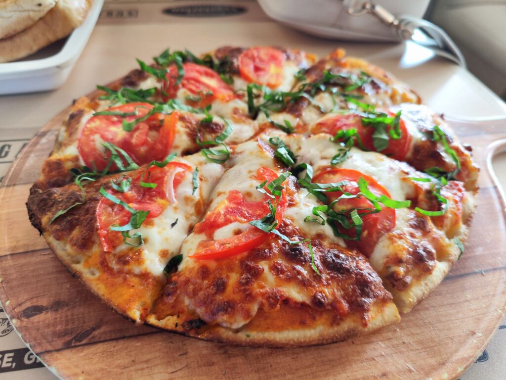 Gros plan d'une pizza Margherita fraîche aux tomates et au basilic. Idéale pour promouvoir la cuisine italienne.