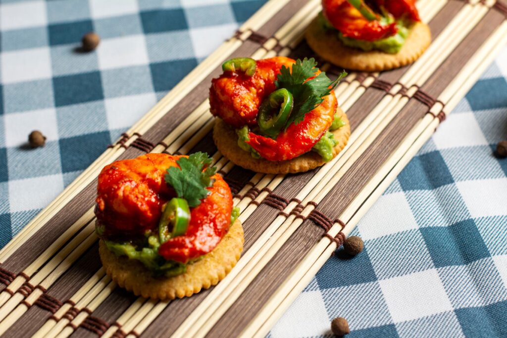 Savoureux apéritifs aux crevettes avec guacamole et jalapeños servis sur des craquelins.