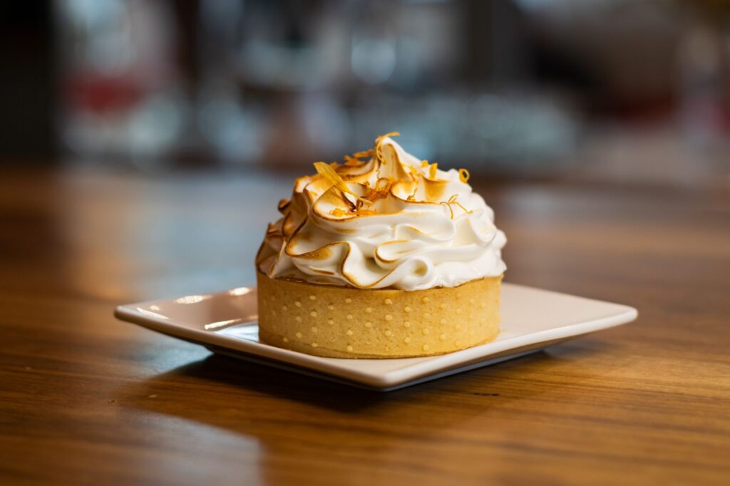 Une délicieuse tarte au citron meringuée sur une assiette carrée, parfaite pour les amateurs de desserts.