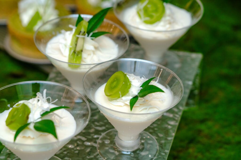 Un délicieux parfait à la noix de coco garni de tranches de kiwi et de copeaux de noix de coco, servi dans d'élégants verres.