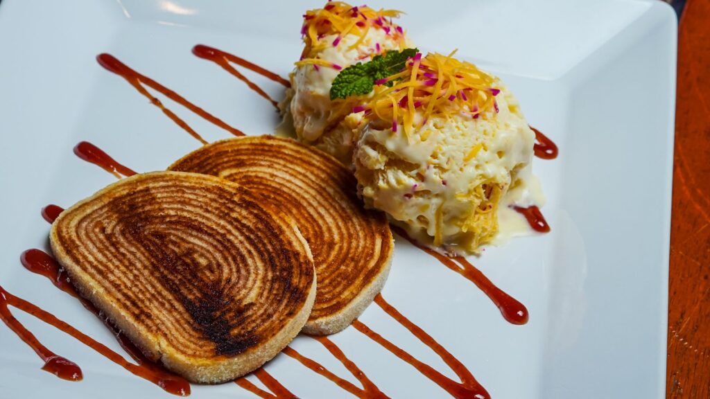 Gros plan sur du pain grillé accompagné de crème glacée arrosée de sauce, garnie de menthe.