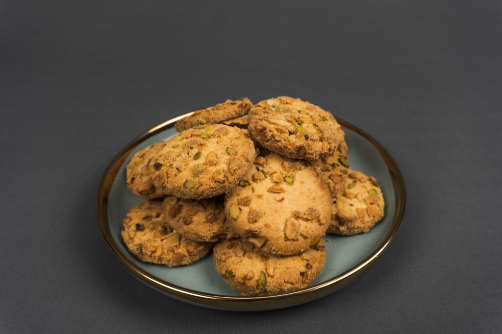 Une pile de délicieux biscuits aux noix sur une assiette bleue sur un fond sombre.