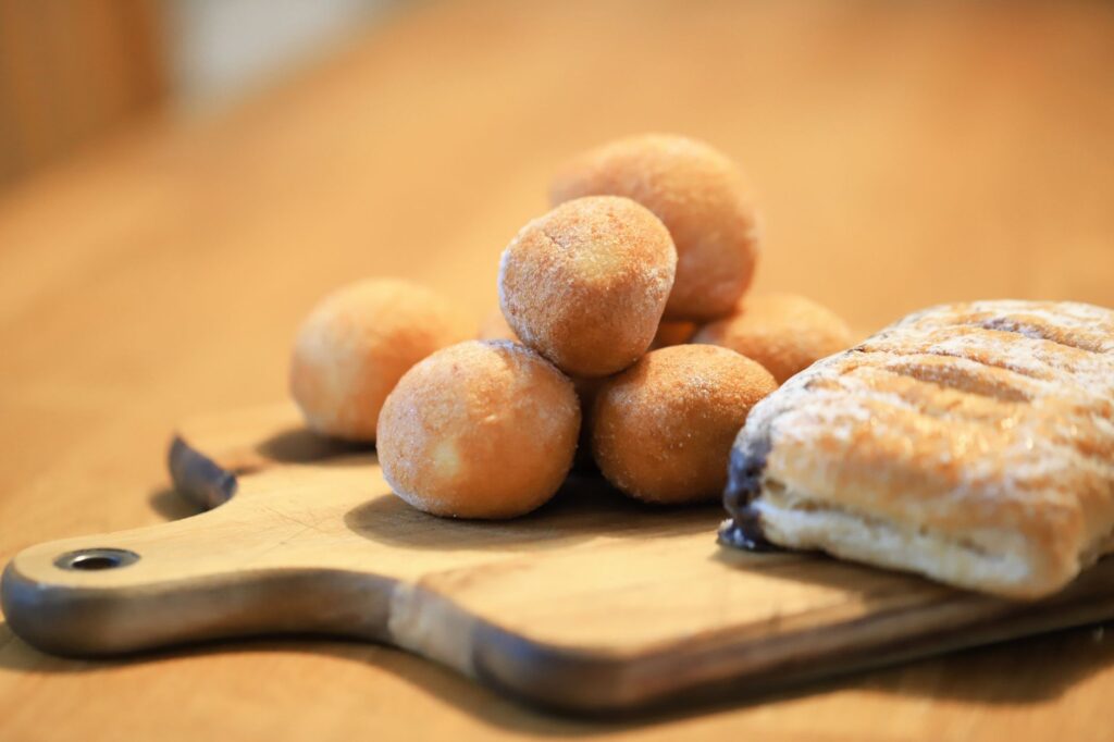 Gros plan d'une variété de pâtisseries, dont une pâte feuilletée et des beignets, disposés sur une planche de bois.