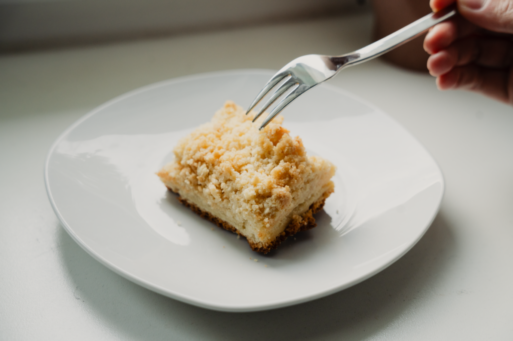 Gros plan d'une seule tranche de streuselkuchen sur une assiette, avec une fourchette prête à creuser.