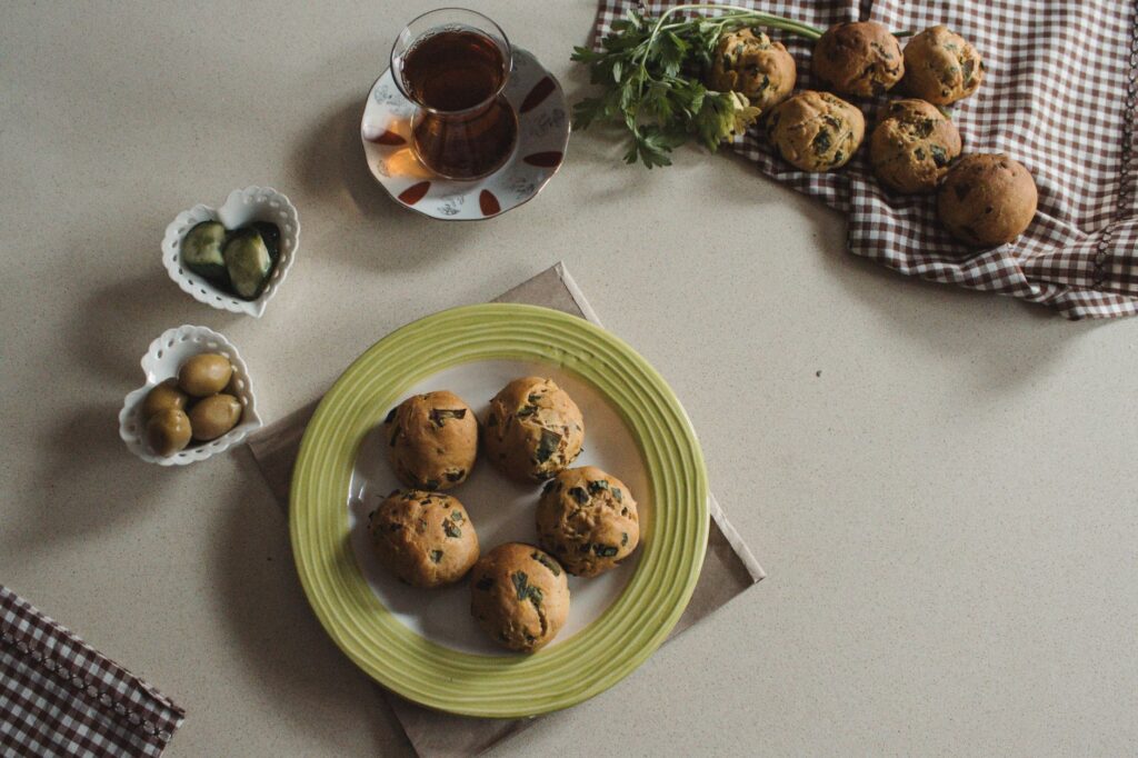 Une jolie présentation de muffins aux herbes faits maison servis avec du thé, des olives et des légumes.