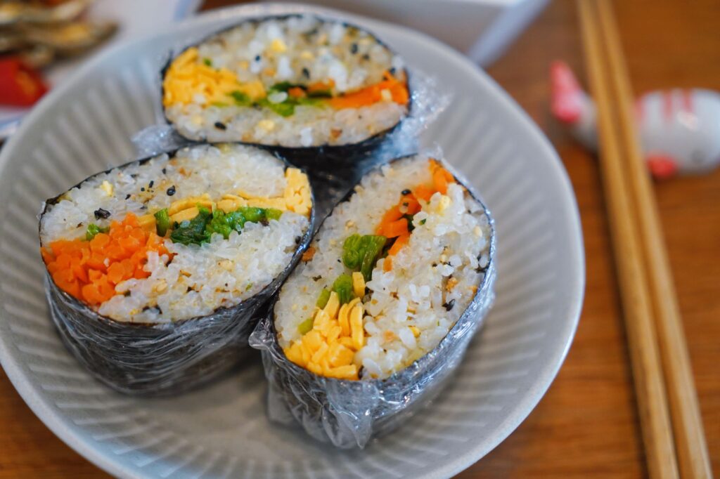 Gros plan sur une assiette de sushis faits maison garnis de carottes, d'œuf et de légumes verts, un régal pour les gourmets.