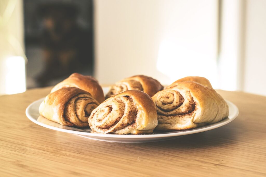 Des roulés à la cannelle chauds et invitants sur une assiette blanche, parfaits pour une douceur.