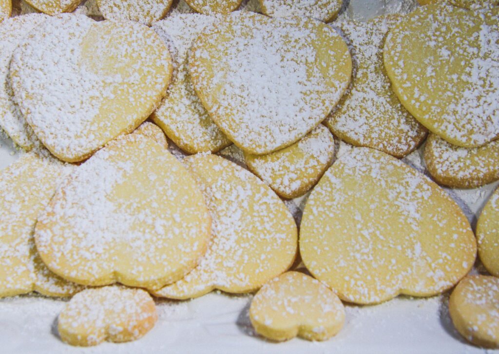 Un tas de biscuits au sucre en forme de cœur saupoudrés de sucre glace. Parfaits pour la Saint-Valentin.
