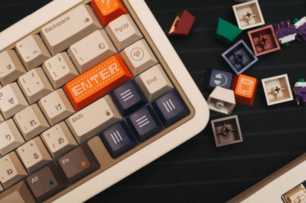 Vue de dessus d'un clavier mécanique beige avec des touches personnalisées colorées et des interrupteurs détachés à proximité.