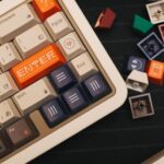 Vue de dessus d'un clavier mécanique beige avec des touches personnalisées colorées et des interrupteurs détachés à proximité.