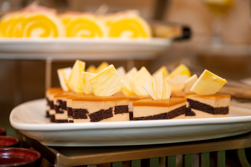 Pâtisseries raffinées en couches de chocolat et de caramel, garnies de chocolat blanc sur un plat de service.