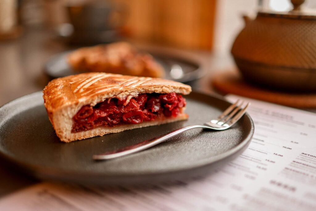Une part de tarte aux cerises délicieuse servie sur une assiette en céramique, parfaite pour les amateurs de desserts.