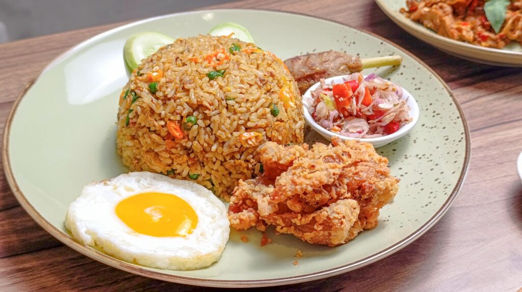Un délicieux plat de riz frit asiatique avec œuf au plat, poulet frit et légumes frais.
