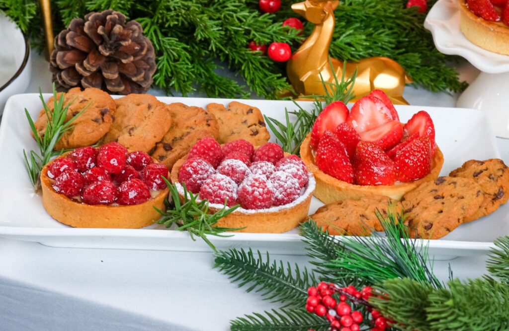 Un délicieux assortiment de gourmandises festives, avec des tartelettes aux fruits rouges et des biscuits, sur une table de fête.
