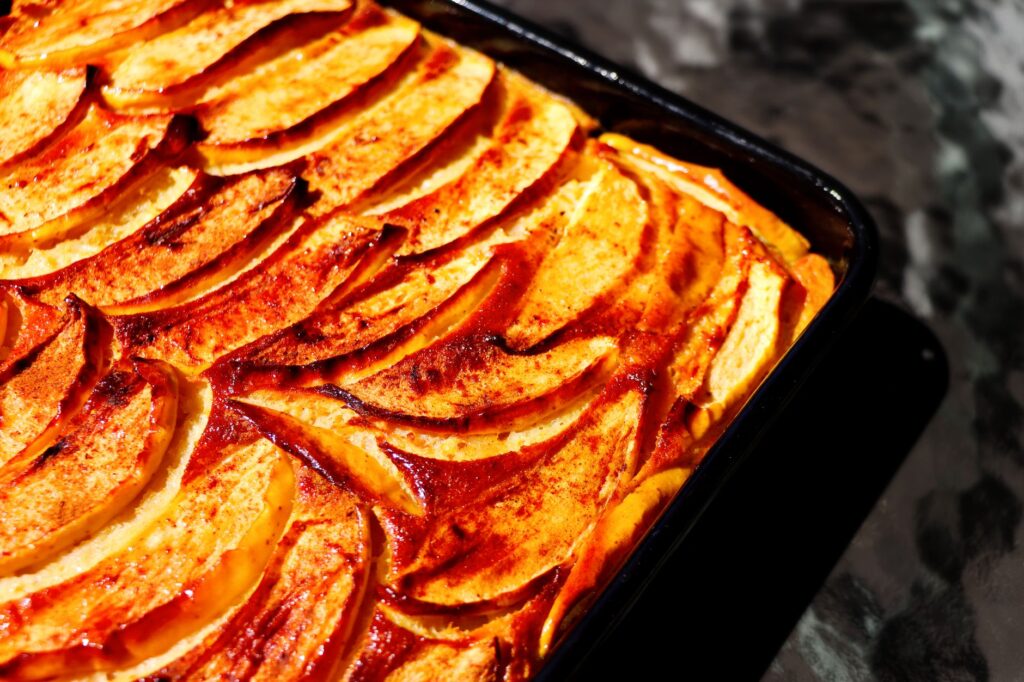 Un délicieux gâteau maison aux pommes et à la cannelle, tout juste sorti du four, avec ses tranches de pommes dorées et cuites au four.
