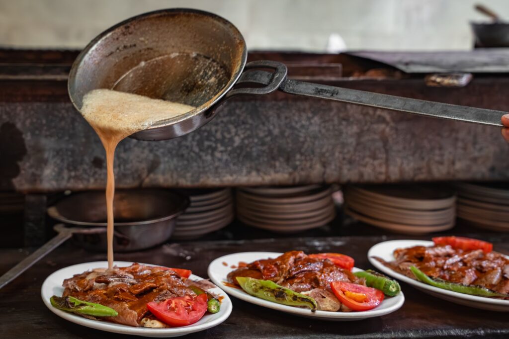 Authentique kebab Iskender avec sauce servi dans des assiettes, capturant l'art culinaire turc.