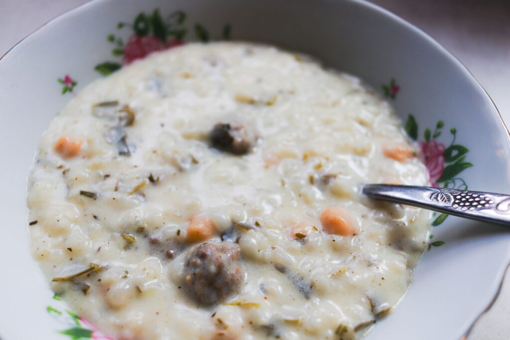 Gros plan sur une soupe crémeuse aux légumes et à la viande servie dans un bol à motifs floraux, avec une cuillère.