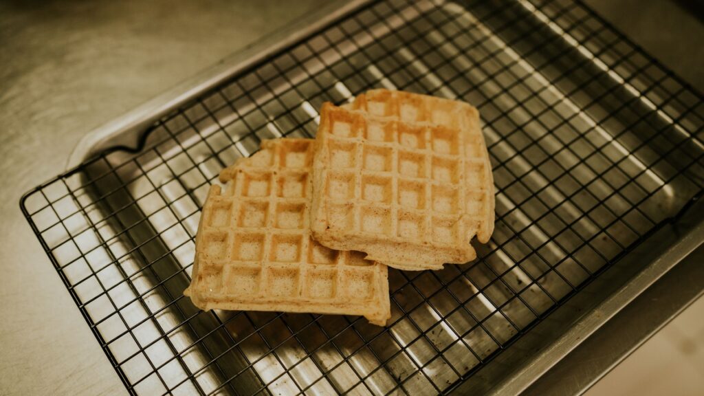 Deux gaufres dorées, fraîchement cuites, sur une grille de refroidissement dans une cuisine.