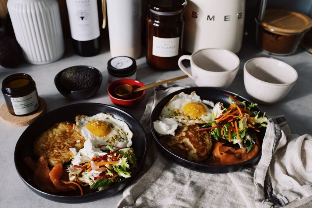 Délicieux brunch avec des œufs, une salade et du saumon fumé servi sur des assiettes noires.